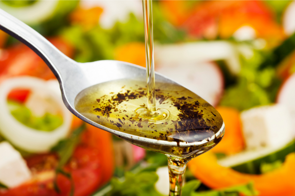 A close up of a spoon with oil and vinegar dripping off it